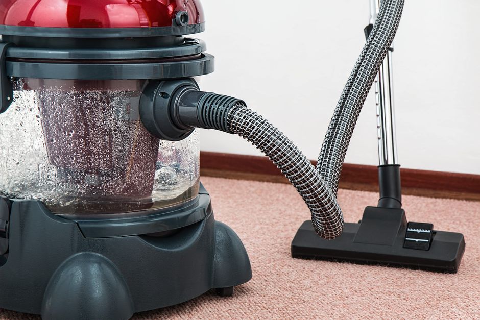 Close-up of a modern vacuum cleaner with water filtration on carpet floor indoors.