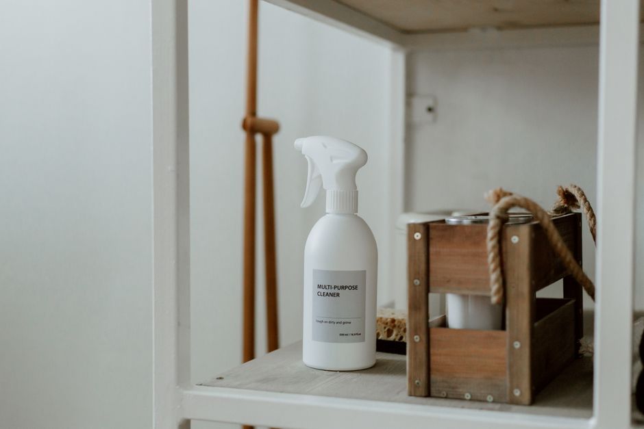 Clean white shelf with a spray cleaner and wooden caddy, perfect for home organization.